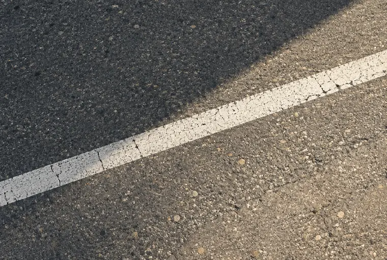 Nahaufnahme von Asphalt mit weißer Fahrbahnmarkierung